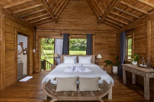 a bedroom with a large bed in a wooden room at Kawiya Healing Retreat Sanctuary in Tampaksiring