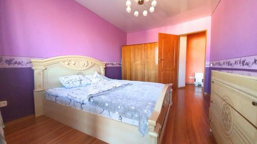 ein Schlafzimmer mit einem weißen Bett mit lila Wänden in der Unterkunft 2-х комнатная квартира в центре in Qaraghandy