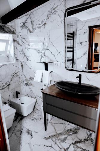 a marble bathroom with a sink and a mirror at Hotel Tradita in Shkodër