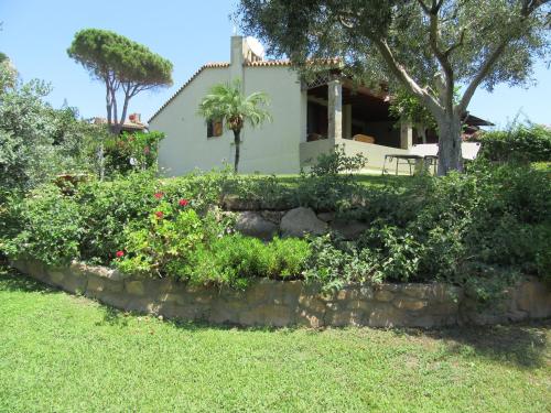 a house with a stone wall and some bushes at Dany in Costa Rei