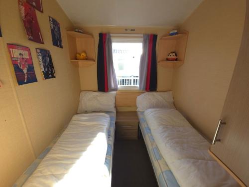 two beds in a small room with a window at The Retreat Palm - Lido Beach Prestatyn in Prestatyn