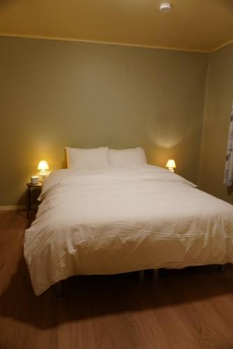 - un grand lit blanc dans une chambre avec deux lampes dans l'établissement Arctic View House - near Cable Car & Arctic Cathedral, à Tromsø