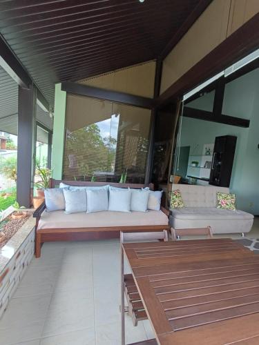 a patio with a couch and a table and windows at Casa inteira 3 quartos Centro Pomerode Pousada in Pomerode