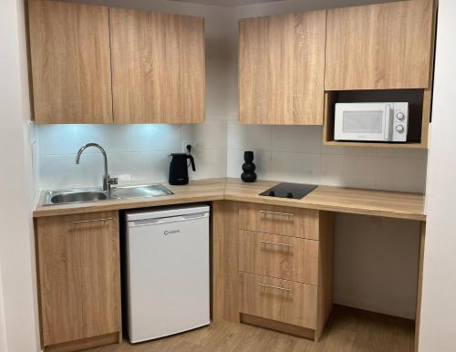a kitchen with wooden cabinets and a white dishwasher at Zenao Appart'hôtels Alfortville in Alfortville