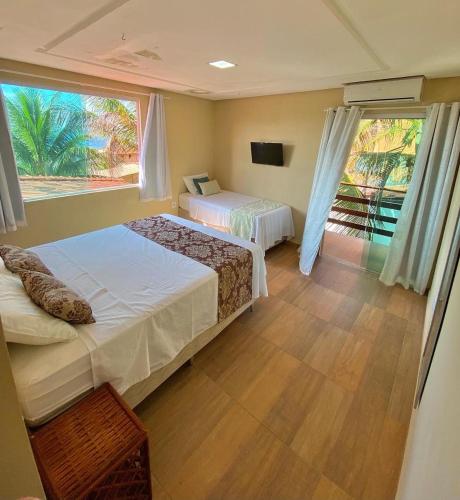 a hotel room with two beds and a window at Pousada Rosa do Mar in Gamboa
