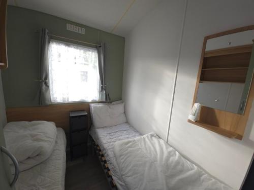 ein kleines Zimmer mit zwei Betten und einem Spiegel in der Unterkunft The Retreat at Marine Holiday Park in Rhyl