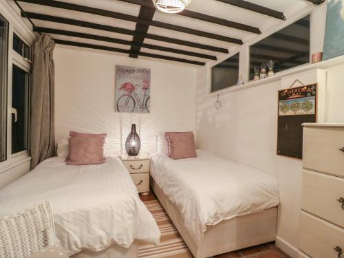 twee bedden in een kamer met witte muren bij Berkley Cottage in Coggeshall