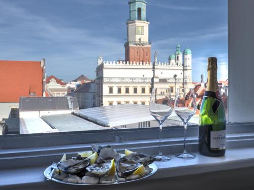 ポズナンにあるOysters & Bubbles Gastro Rooms Rynek Squareの牡蠣の皿とワインのボトルとグラス
