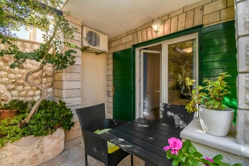 a wooden bench sitting on a patio with potted plants at Apartments and Room Napoli in Bol