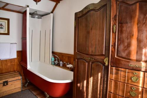 a bathroom with a tub and a sink and a wooden cabinet at Hobbit Boutique Hotel in Bloemfontein