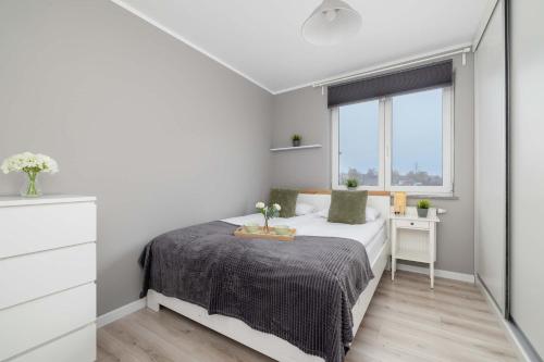 a white bedroom with a bed and a window at Modern 2-Bedroom Apartment with Remote Workspace in Katowice by Noclegi Renters in Katowice