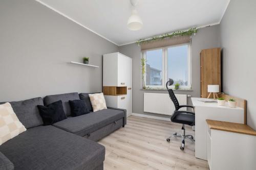 a living room with a couch and a desk at Modern 2-Bedroom Apartment with Remote Workspace in Katowice by Noclegi Renters in Katowice