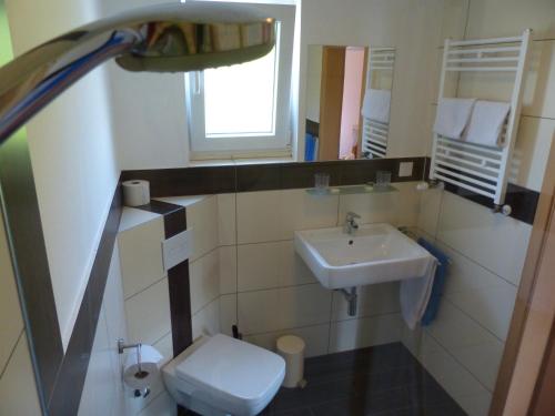 ein Badezimmer mit einem Waschbecken, einem WC und einem Spiegel in der Unterkunft Haus der Gastlichkeit in Ratingen