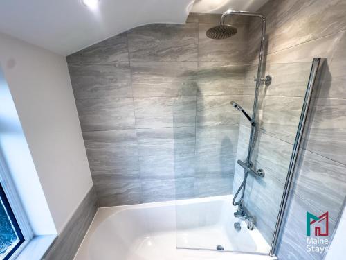 La salle de bains est pourvue d'une douche et d'une baignoire avec une porte en verre. dans l'établissement Modern 3 Bedroom Home, 6 beds, Free Parking, 500MBS, Netflix, Near Coventry City Centre & Hospital, Contractors, Families, Apple Air Play, à Coventry
