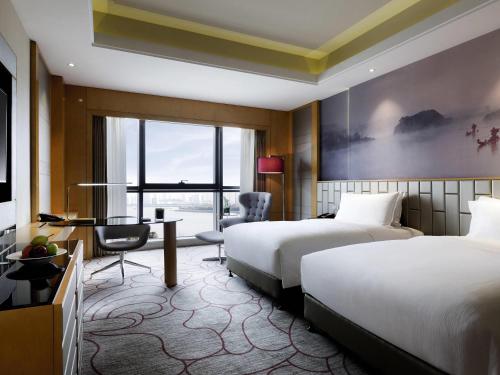 a hotel room with two beds and a desk at Pullman Wenzhou in Wenzhou