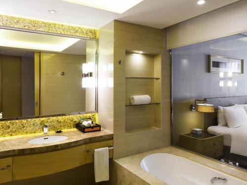 um banheiro com banheira, pia e cama em Pullman Changshu Leeman em Changshu