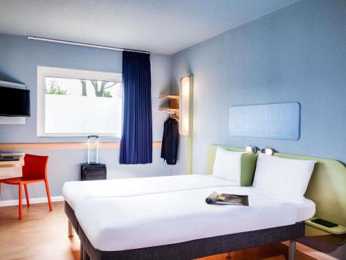 a bedroom with a bed and a desk with a chair at ibis budget London Barking in Barking