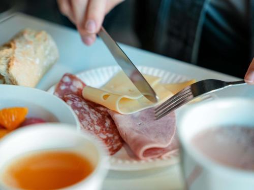una persona sosteniendo un tenedor y un cuchillo y un plato de comida en ibis budget Sète centre, en Sète