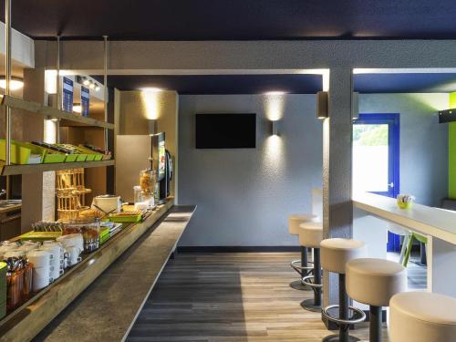 un restaurante con bar con taburetes y mostrador en Ibis budget Rouen Petit Quevilly, en Le Petit-Quevilly