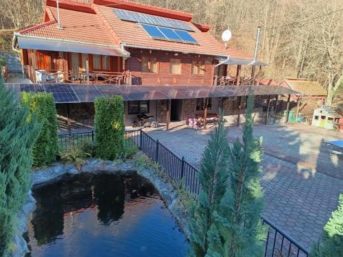 ein Haus mit einem Teich davor in der Unterkunft Cabana FARIO Rau Mare - Retezat in Clopotiva