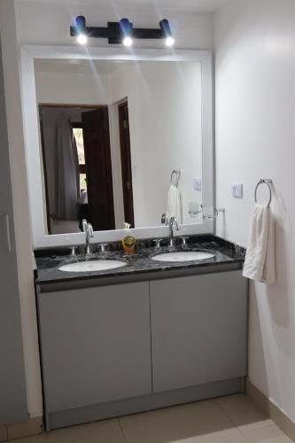 un bagno con due lavandini e un grande specchio di Cabañas Casa Blanca a El Mollar