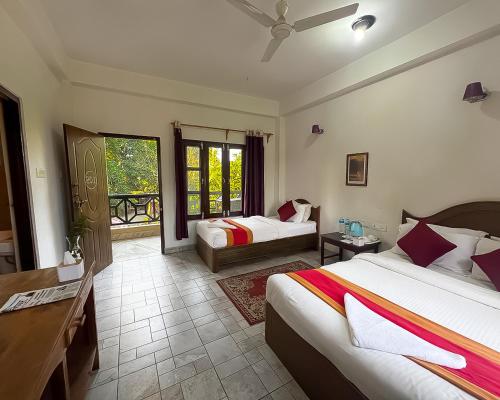 um quarto com duas camas, uma escrivaninha e uma janela em Chitwan Park Village em Sauraha