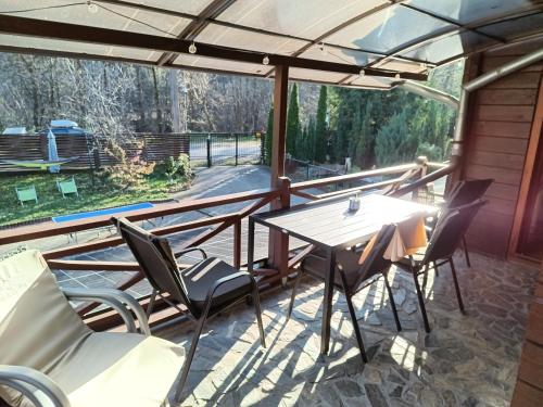 eine abgeschirmte Veranda mit einem Tisch und Stühlen in der Unterkunft Cabana FARIO Rau Mare - Retezat in Clopotiva
