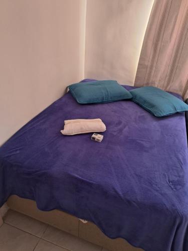 ein violettes Bett mit zwei Kissen und einem Handtuch darauf in der Unterkunft Pousada da Mari in São Gabriel