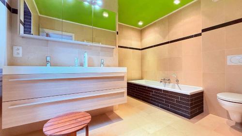 a bathroom with a tub and a toilet and a sink at Villa La Chauve Souris in Houffalize