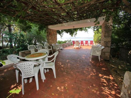 eine Terrasse mit weißen Stühlen sowie einem Tisch, Tischen und Stühlen in der Unterkunft Holiday Home in Starigrad by the Beach in Starigrad-Paklenica