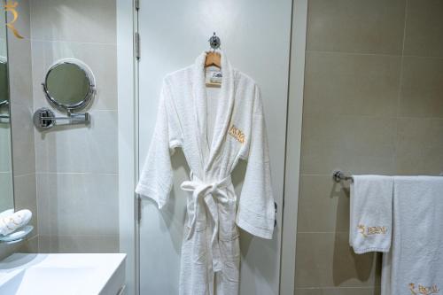 a robe hanging on a shower door in a bathroom at Bright 1BR with Balcony the Gate, Masdar City in Abu Dhabi