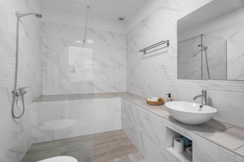 Un baño blanco con lavabo y ducha en 1 Apartamentos Omanai Tenerife Sur, en Las Galletas