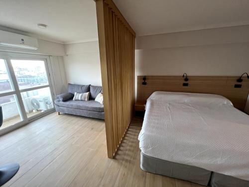 a bedroom with a bed and a couch and a window at Stuart's Apartment in Mar del Plata