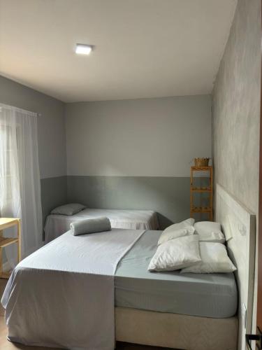 une chambre avec deux lits avec draps blancs et oreillers dans l'établissement Suite familia - Centro de Itu, à Itu