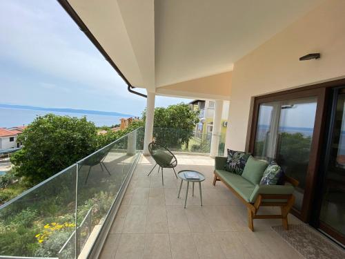 eine Terrasse mit einer Couch und einem Tisch auf einem Balkon in der Unterkunft Renovierte Ferienwohnung in Ravni mit Schöner Terrasse und Meerblick in Ravni