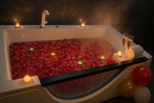 Urban homestay volcastay في Zirakpur: حوض استحمام مملوء بالورود الحمراء مع الشموع وكؤوس النبيذ