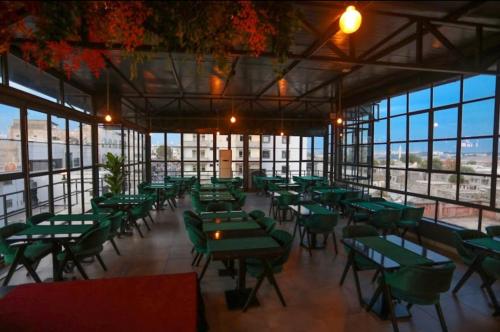 een restaurant met groene tafels, stoelen en ramen bij Sur Central OTEL in Diyarbakır