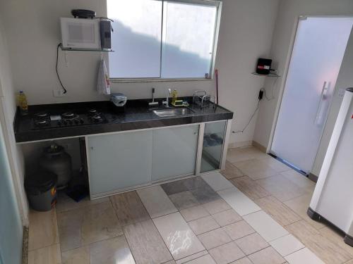 a kitchen with a counter with a sink and a microwave at Kitnet Boa Vista in Sete Lagoas