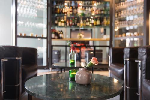 a table in a bar with a vase with a flower on it at Elite Hotel Arcadia in Stockholm