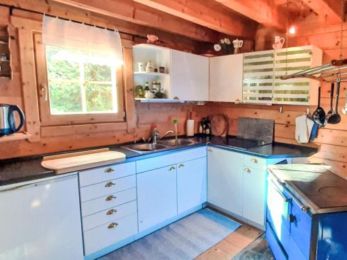 une cuisine avec des armoires bleues, un évier et une fenêtre dans l'établissement Holiday Home Zirbenwaldhütt'n by Interhome, à Brandstätter