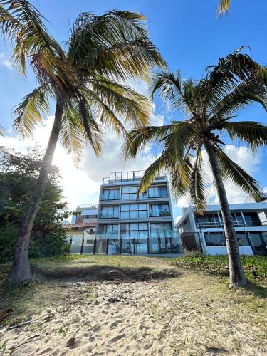 zwei Palmen vor einem Gebäude in der Unterkunft Melhores Flats - Seu desejo, pé na areia in Tambaú