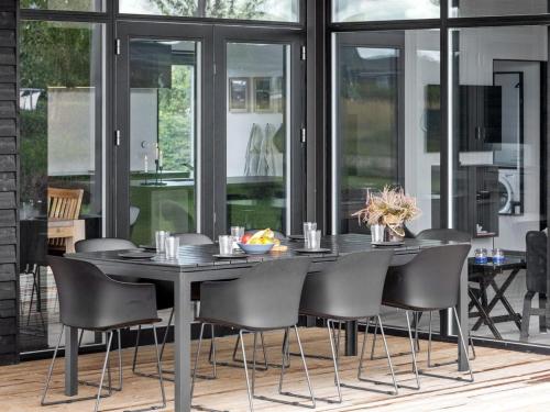 a black dining table and chairs in a room with windows at Holiday Home Emelina - 300m from the sea by Interhome in Rude