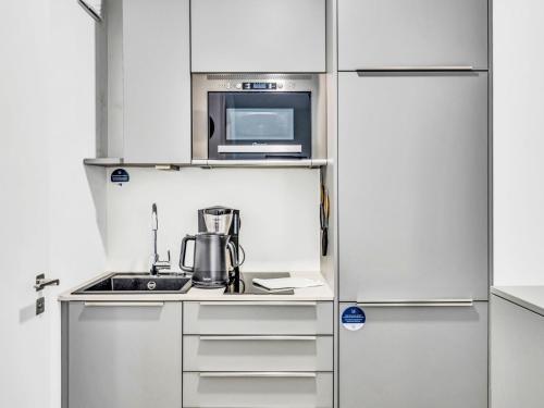 a kitchen with white cabinets and a microwave at Apartment Seeruhe by Interhome in Lembruch