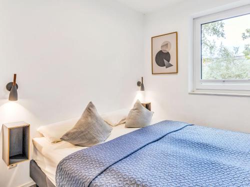 a bedroom with a bed with a blue comforter and a window at Apartment Seeruhe by Interhome in Lembruch