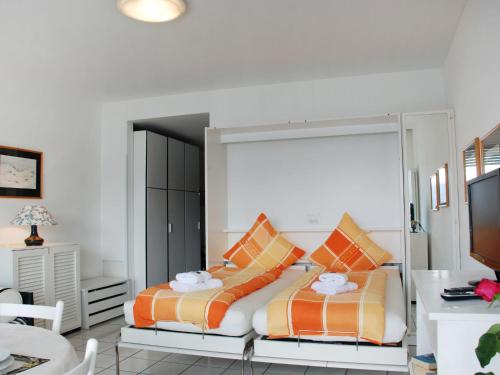een slaapkamer met een bed met oranje en witte kussens bij Studio Vista Lago by Interhome in Ruvigliana
