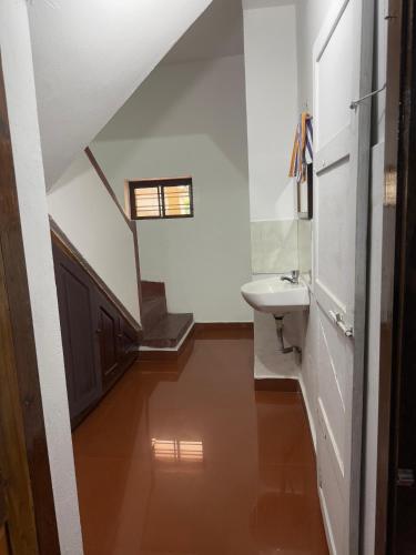a bathroom with a sink and a toilet and a staircase at Urban Minz in Mūvattupula
