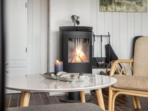 Una chimenea en una sala de estar con una mesa y una vela. en Apartment Ketilbiorn - 700m from the sea by Interhome, en Rødhus