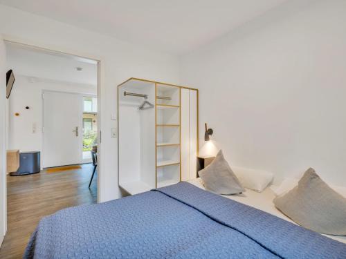 a white bedroom with a blue bed and a mirror at Apartment Seetraum by Interhome in Lembruch