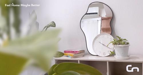 a mirror on a shelf with a plant and a clock at Jarrdin Apartment by CozyNest Syariah in Bandung