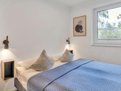 a bedroom with a bed with a blue comforter and a window at Apartment Seeleuchten by Interhome in Lembruch